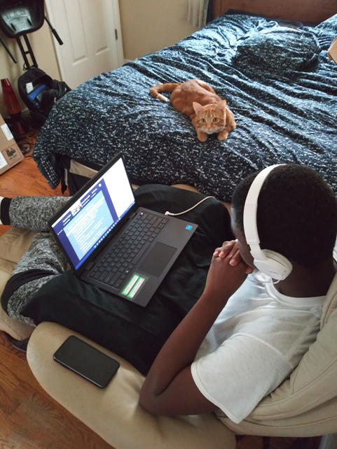 A Student Wearing Headphones And Using A Laptop